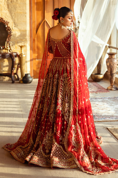 Side profile of NAQSHI Firaaq showing flowing net lehenga flare adorned with embellished panels, malicious borders and texture-play embroidery in apple-red tone.