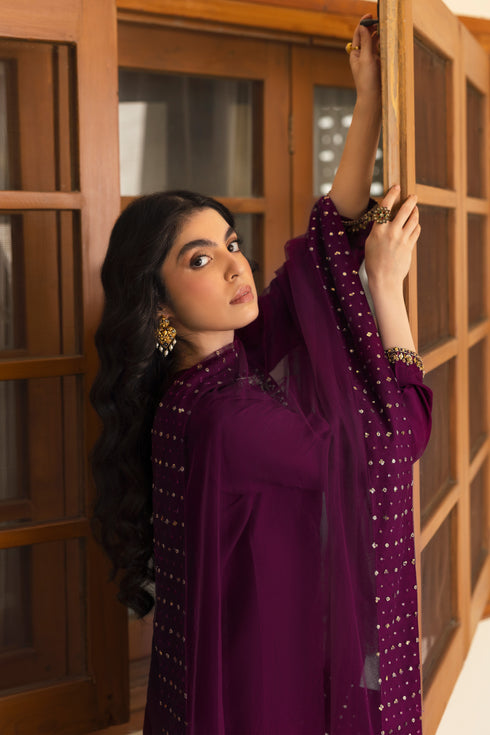 Model wearing full NAQSHI Irma 3PC: wine-purple embellished raw-silk shirt, olive-green embroidered culottes & net dupatta with thick hand-adda border for a youthful, layered look.