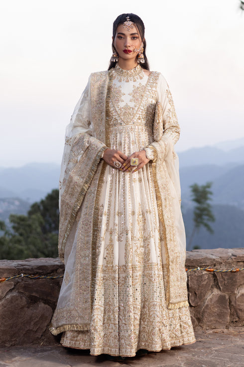 Naqshi Fasana dove‑white floor‑length raw‑silk frock with halter neckline, deep back, heavy hand‑adda—kora, dabka, sitari, tilla, crystal embellishments—and structured pouch.