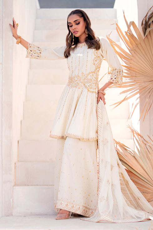 Side view of Diana showing peplum cutline, embellished sleeve cut‑work, sharara flare, and delicate net dupatta fall.