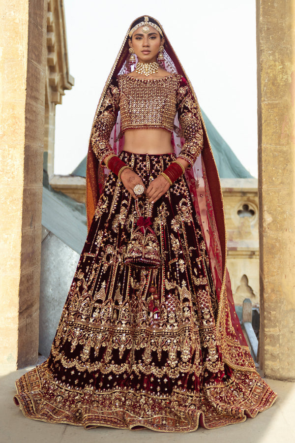 NAQSHI Parivarsh deep‑maroon velvet choli with round neckline and fitted three‑quarter sleeves, heavily embellished with hand‑adda—naqshi, dabka, sitari, cut dana, stonework, crystals—paired with voluminous velvet lehenga.