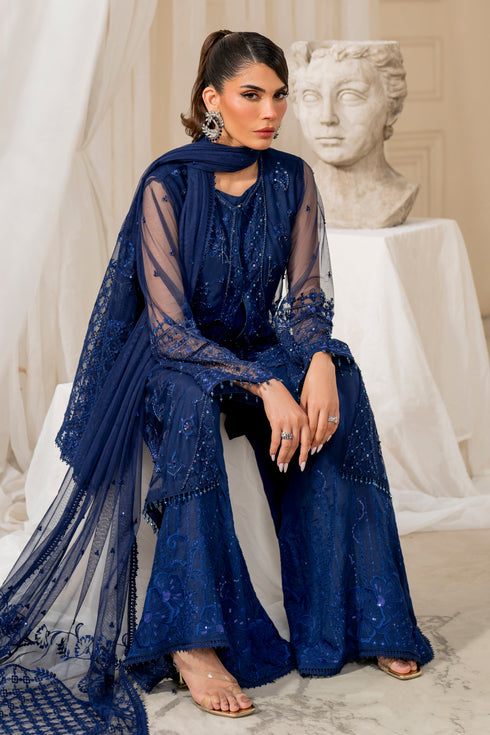 Model wearing full naqshi nayal 4PC set: navy‑blue embellished net gown, flared culottes, embroidered dupatta styled for graceful formal appearance.