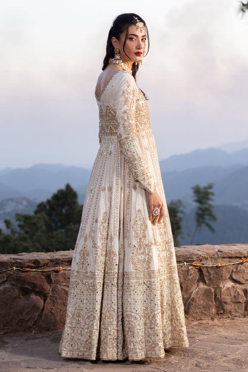 Side view of Naqshi Fasana showcasing voluminous paneled skirt, extended sleeves, mirror‑embedded border and luxe raw‑silk texture.