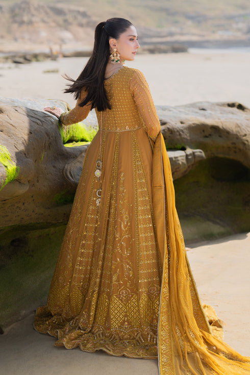 Side spinning view of NAQSHI Ainara showcasing full flare of floor‑length frock with alternating floral and geometric embroidered panels in mustard and yellow tones.