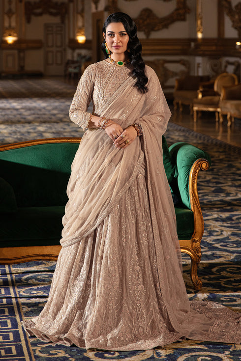 Naqshi Areeza skin‑gold net choli richly embroidered with hand‑adda motifs, sequin detailing, scalloped sleeves with dangling tassels, paired with voluminous lehanga.