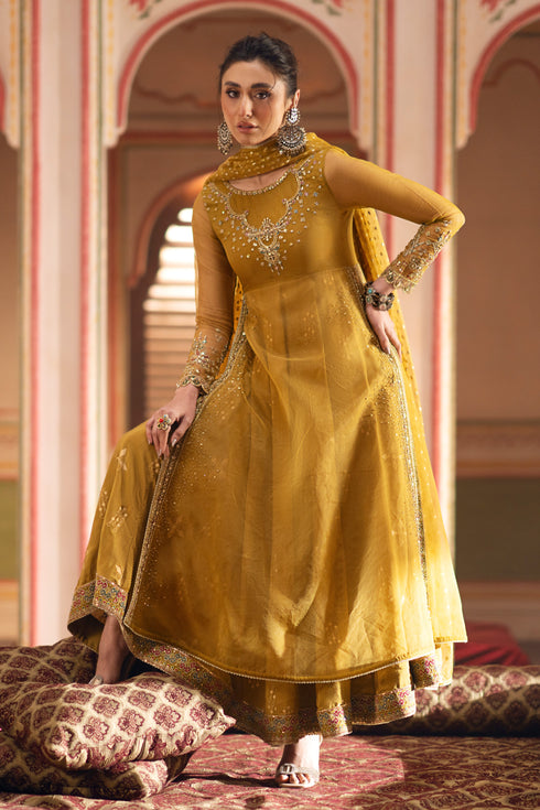 NAQSHI Mehrosh mustard organza frock with intricate neckline embroidery and semi-sheer sleeves, paired with flared raw-silk trousers and tassel-adorned dupatta.