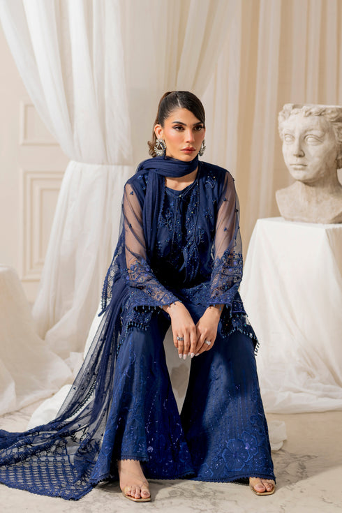 Model wearing full naqshi nayal 4PC set: navy‑blue embellished net gown, flared culottes, embroidered dupatta styled for graceful formal appearance.