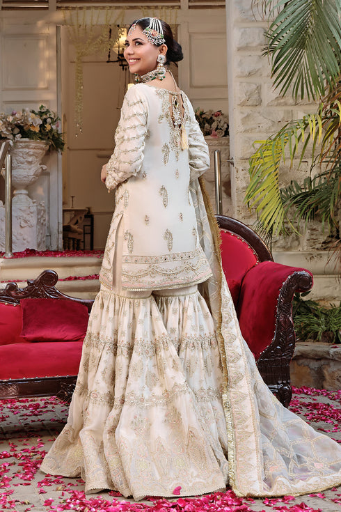 Side shot of Zonar showcasing shirt’s fitted cut, scalloped and tasseled sleeves, mirror motifs, and full volume gharara in matching organza.