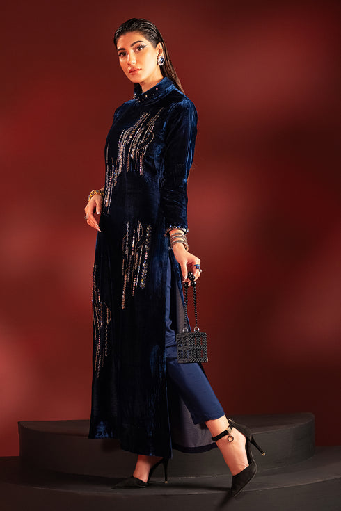 Walking pose of neon blue velvet formal dress highlighting straight silhouette and hand embellished neckline, ready to wear evening wear.