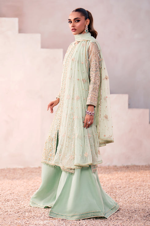 Side shot of Naqshi Parsa showcasing mid‑front slit with piping details, side‑seam embroidery, layered sharara flare and delicate dupatta drape.