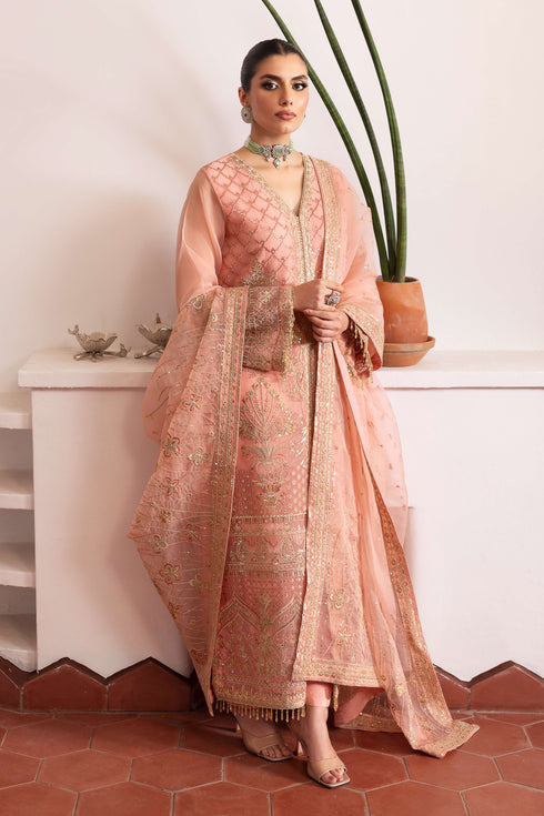 Model wearing full NAQSHI Muzna set: flamingo‑pink embroidered organza gown, straight PK‑silk trousers & heavily detailed dupatta styled for a cohesive look.