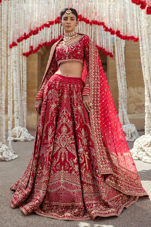 Side profile of NAQSHI Qurbat showcasing lehenga flare, hand-adda motif paneling across skirt, and scalloped sleeve drape in raw-silk cutline.