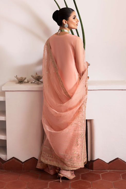 Side profile of NAQSHI Muzna showcasing flowy organza gown silhouette, embroidered V‑neck panel, fluid side slit, crystal‑trim sleeve ends and silk trousers.