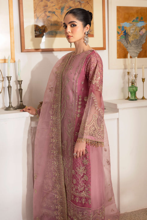 Side look at NAQSHI Nayab showing organza shirt silhouette with berry-pink embroidered side panels, crystal hangings on sleeves, and matching culottes.