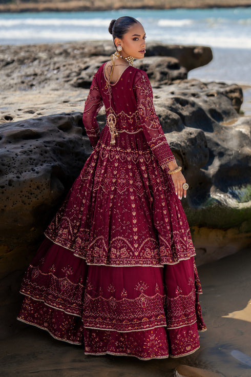 Model wearing full NAQSHI Zureal 3PC set: layered burgundy crinkle frock with heavy embroidery and tassels, raw-silk pants & matching embroidered dupatta styled for evening elegance.