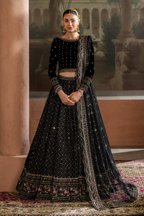Woman in a black embroidered traditional outfit standing in front of classical architecture.