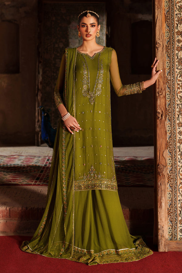 Woman in a green traditional outfit standing in a decorated room.