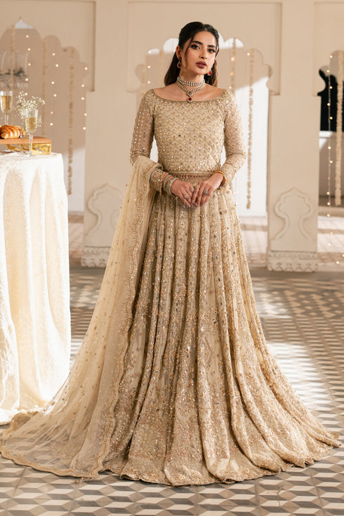 Woman in a sparkling gold evening gown standing in an elegant indoor setting.