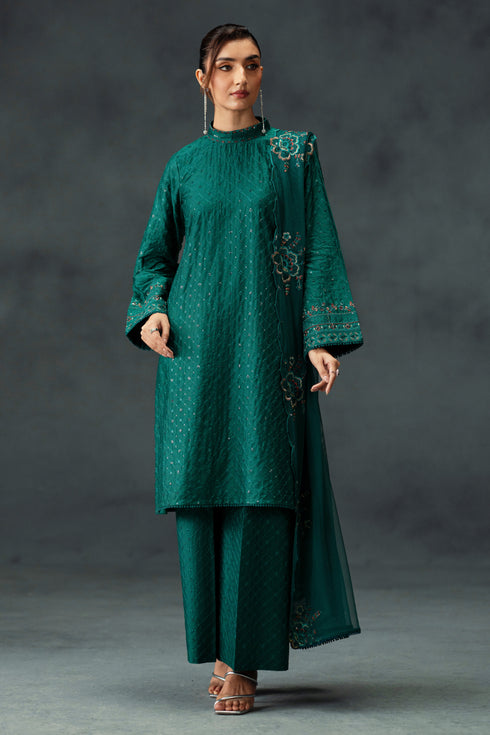 Woman wearing a green traditional outfit with intricate patterns on a dark background