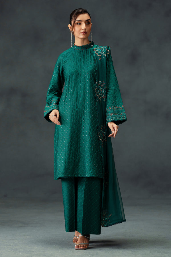 Woman wearing a green traditional outfit with intricate patterns on a dark background