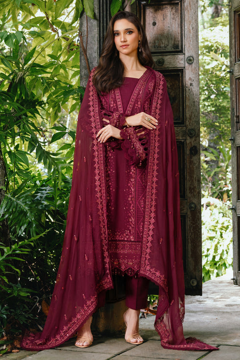 Woman in a burgundy traditional outfit with a matching dupatta standing outdoors.