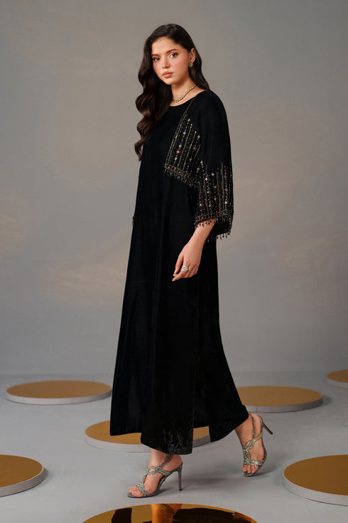 Woman wearing a black dress with beaded sleeves on a gray background