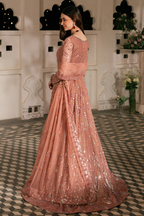 Woman in a pink sequined gown standing in an elegant room with decorative elements.