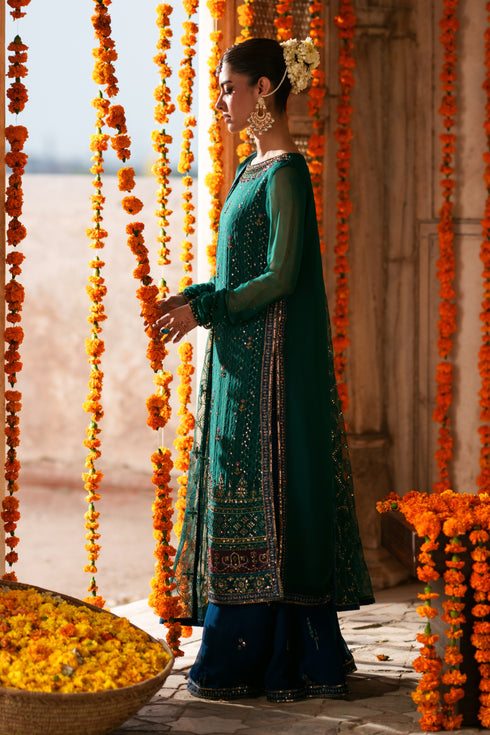 Side view of Anfa green crinkle chiffon semi formal outfit featuring flowing sleeves, blue flary pants and embellished festive detailing