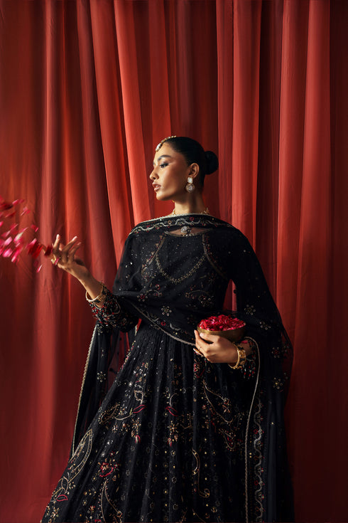 Side profile of NAQSHI Mah Afroz black gown showing flowy panels, angled sleeves, and sequin embroidery detail
