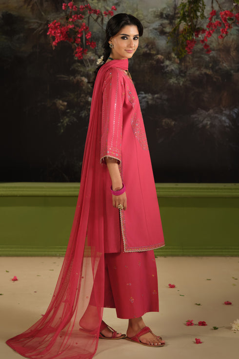 Side view of NAQSHI Kinara carrot pink embroidered Pima lawn shirt paired with cambric culotte trousers and net dupatta