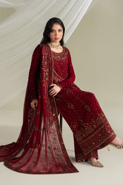 Deep red formal ready-to-wear outfit with flared shirt, culotte, and dupatta, seated pose showing fabric flow and styling
