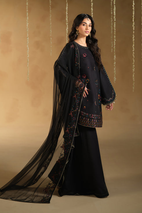 Side view of Lael black festive dress showing round hem shirt silhouette and wide flare pants with net dupatta trail