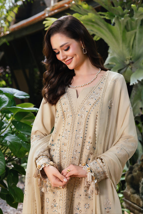 Woman wearing a beige embroidered traditional outfit with green foliage in the background