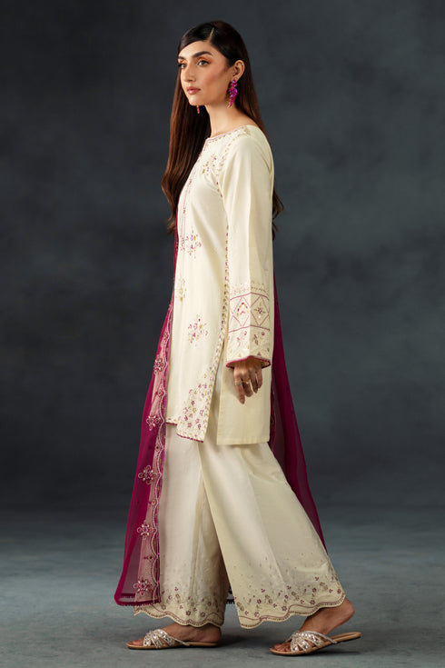 Woman wearing a cream embroidered outfit with a dark background