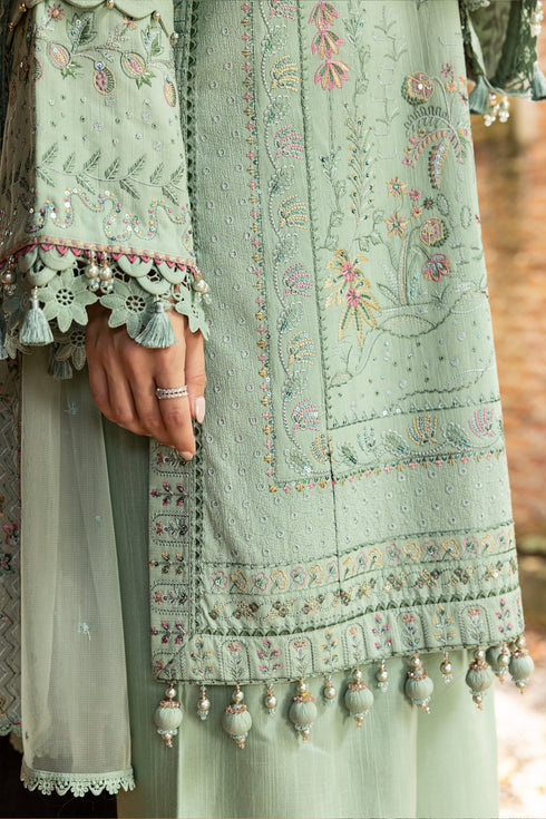 Light green embroidered traditional outfit with floral patterns and tassels.