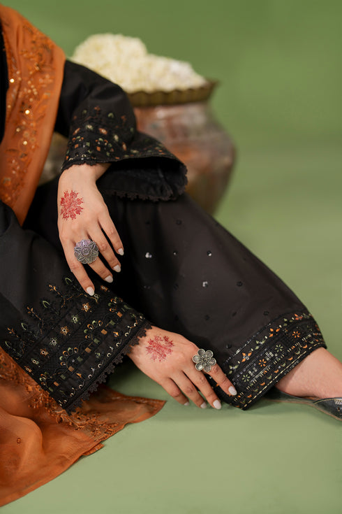 Close-up of NAQSHI Isma trouser hem showing embroidery border detail on black fabric