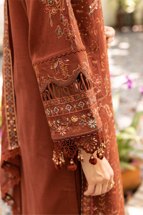 Close-up of a brown embroidered garment with intricate designs and tassels.