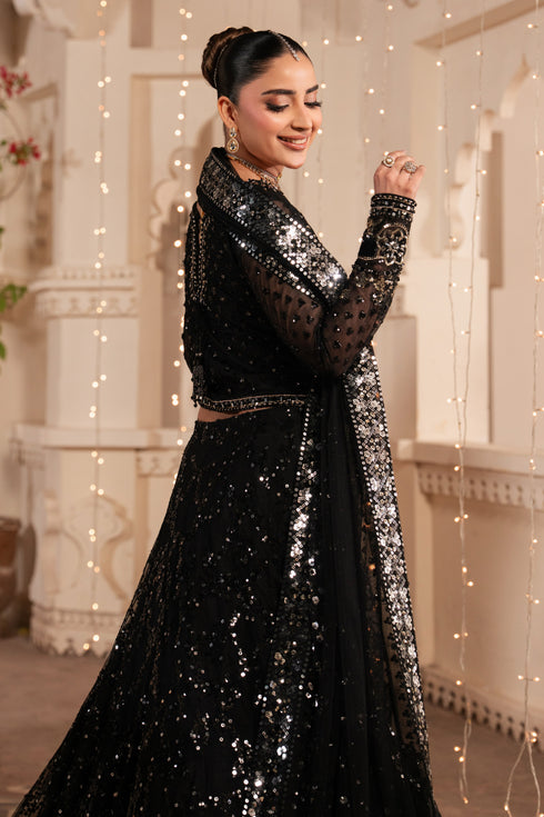Woman in a black sequined outfit standing in a decorated indoor setting with string lights.