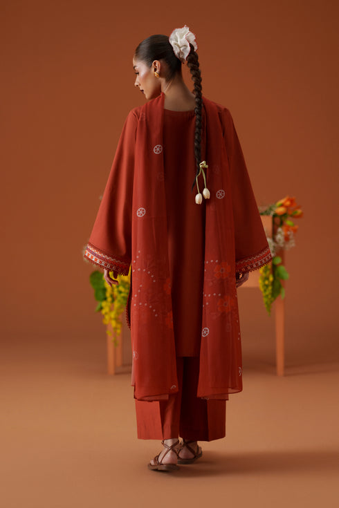 Back view of Ophelia rust 3-piece outfit with long embroidered lawn shirt, printed crinkle chiffon dupatta, and relaxed trouser.