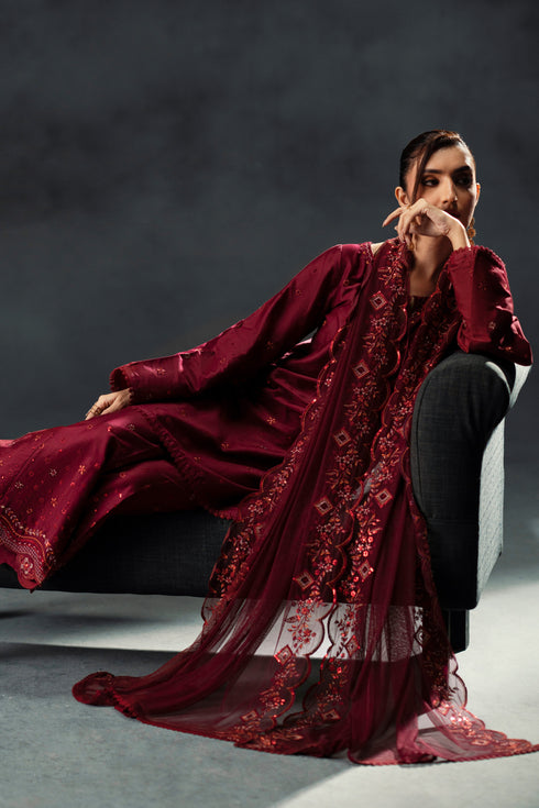 Person wearing a burgundy embroidered outfit against a dark background