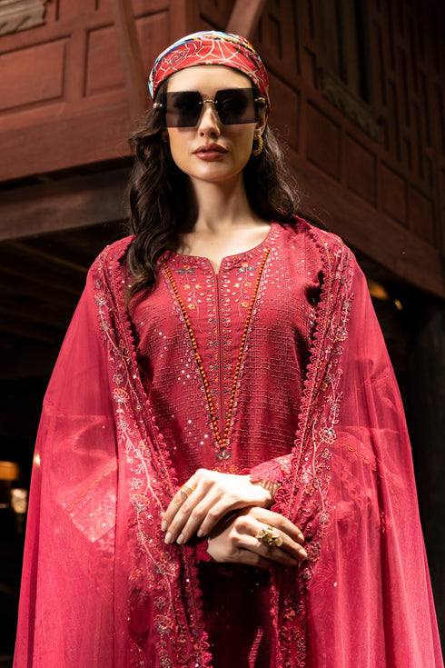 Woman in a red traditional outfit with sunglasses and a headscarf in an indoor setting