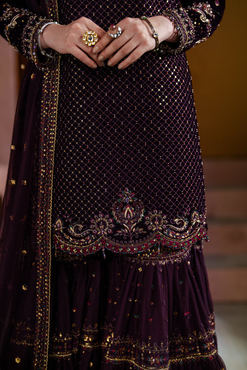 Close-up of a dark purple embroidered traditional outfit with gold details.