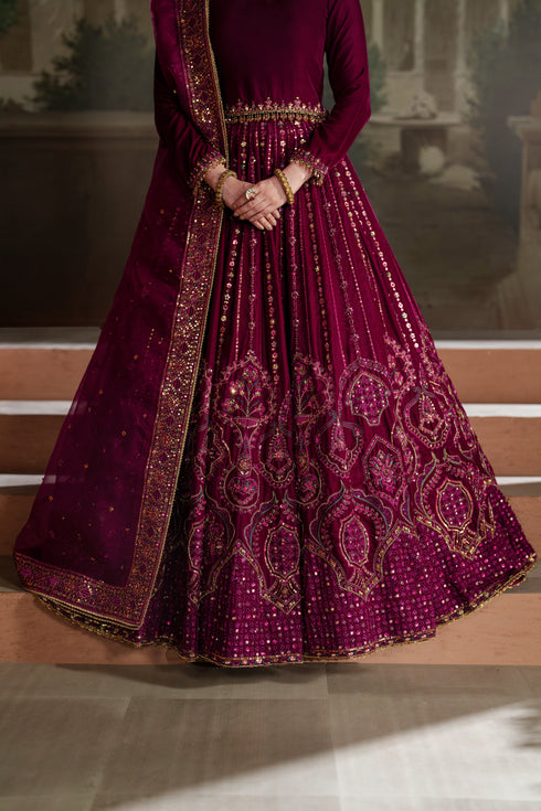 Maroon embroidered traditional outfit with gold details on a wooden floor.