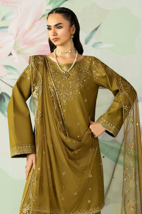 Woman wearing a green embroidered traditional outfit with a dupatta against a floral background