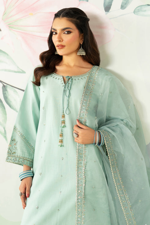 Woman wearing a light blue embroidered traditional outfit with a white background