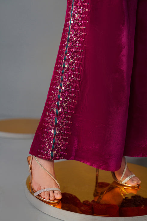 Close-up of a person wearing a magenta outfit with sequin detailing and high-heeled shoes.