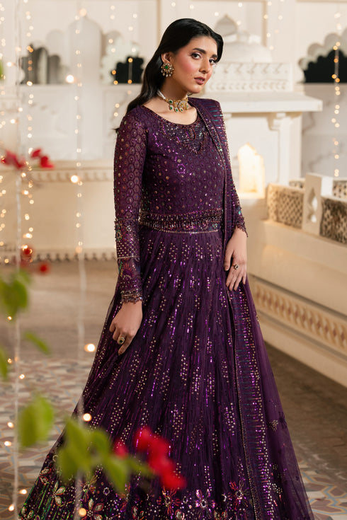 Woman in a purple dress with intricate designs in an elegant indoor setting.