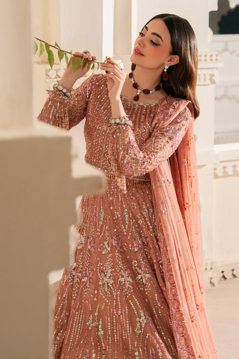 Woman in a detailed pink traditional outfit holding a branch against a light background.