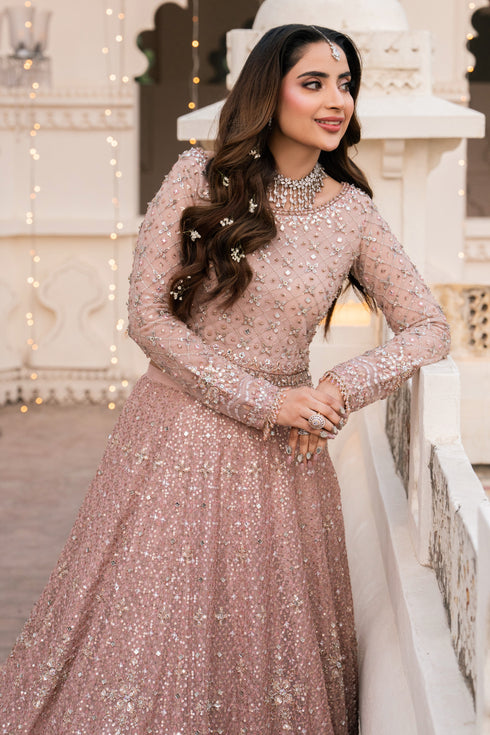 Woman in a sparkling pink dress standing in front of a decorative white structure.