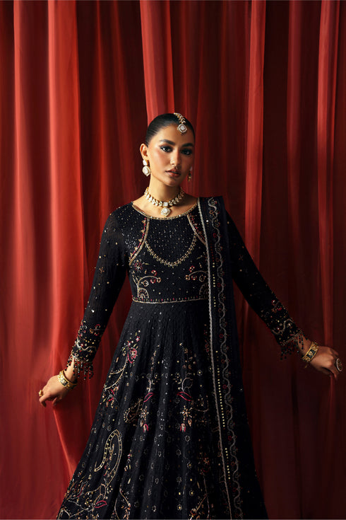 Woman in a black embroidered traditional outfit against a red curtain